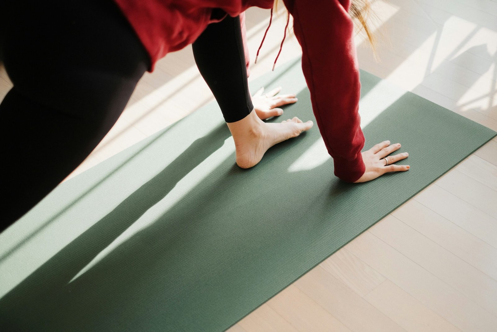 Close-up of a person performing a yoga pose on a green mat, hands and feet on the floor